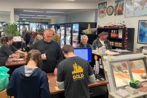 Interior of Sierra Gold Seafood during a busy day. There are customers being helped at the register and many waiting in line behind him.